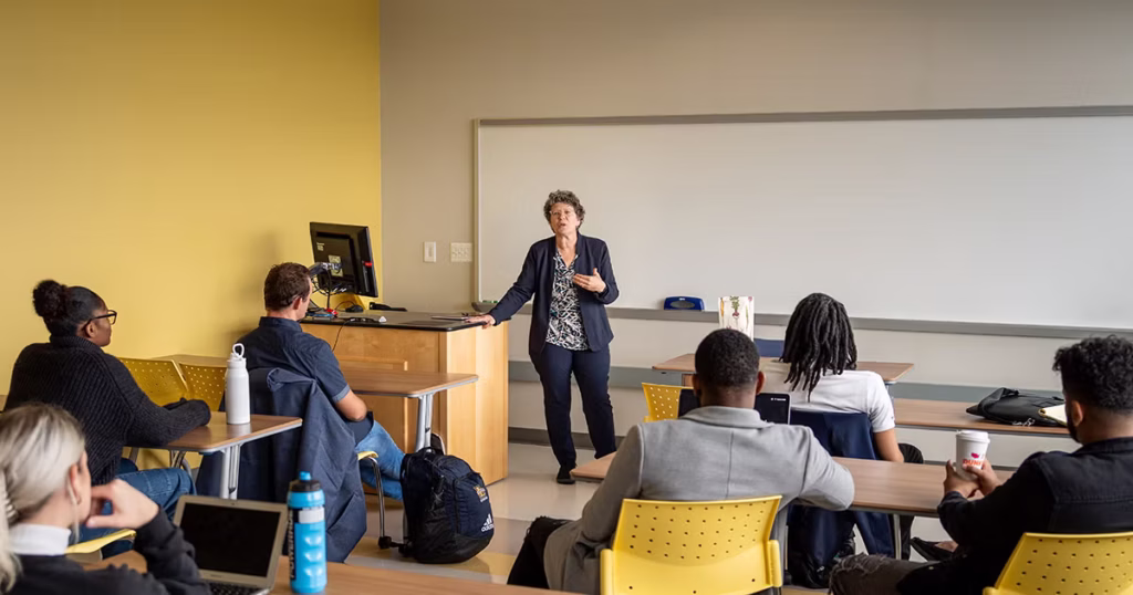 Pauline Scalvino leading a classroom lecture in Founders’ Hall while students attentively listen.